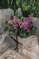 Blooming lilac bouquet in a metal basket on a linen rag with vintage scissors. Beautiful floral background in vintage rustic style.