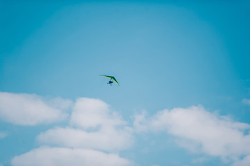The motorized hang glider on blue bright sky
