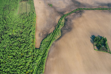 Aerial view over forest and farming fields at warm spring day