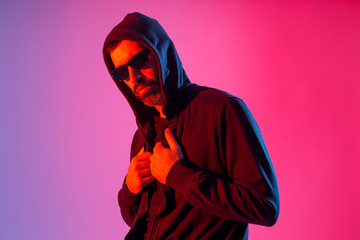 Colorful studio portrait of a bearded man with sunglasses against red and blue background.