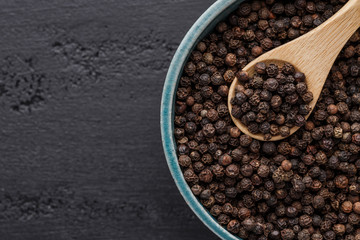 Peppercorn background. Dry black pepper seeds. Top view.On a black background. free space for your text.