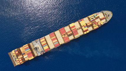 Aerial drone photo of huge colourful truck size container cargo ship cruising open ocean sea