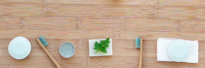 Zero waste bathroom web banner with copy space. Bamboo toothbrushes, solid toothpaste, solid shampoo and soap on wood background. Plastic free, environment concept. Top view, flat lay