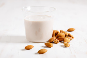 Almond milk in a glass with fresh almond nuts