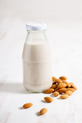 Almond milk in glass bottle with fresh almond nuts