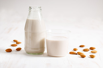 Almond milk in glass bottle with fresh almond nuts