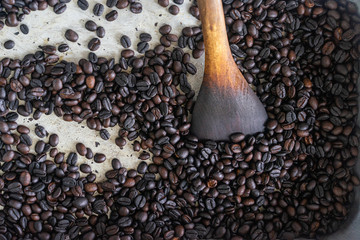 Roasted coffee bean with wooden spatula in steel tray