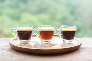 Small cups of dark clear coffee on wooden tray