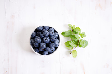 fresh blueberries in ceramics bowl with mint leaves.