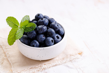 fresh blueberries in ceramics bowl with mint leaves.