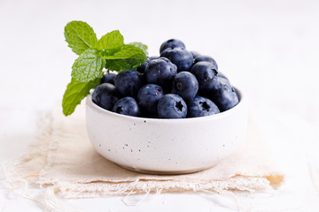 fresh blueberries in ceramics bowl with mint leaves.