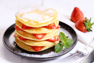 Pancakes with fresh strawberries and maple syrup