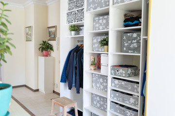 Young handsome European man with dark hair brings wardrobe order puts everything on its place hides things in boxes. Closet organized. Capsule wardrobe.