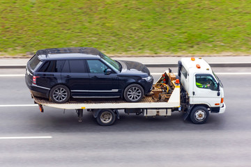 Fototapeta na wymiar Car is transported on an evacuation tow truck on the highway.