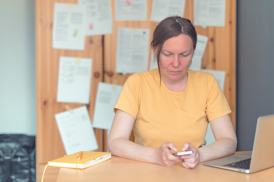 Female freelancer working on smartphone in home office