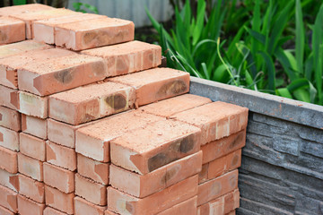 A pile of red bricks are neatly piled together on the construction site to build a brick wall of...