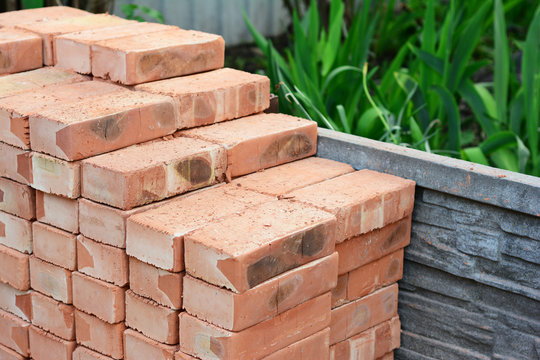 Fototapeta A pile of red bricks are neatly piled together on the construction site to build a brick wall of the house.
