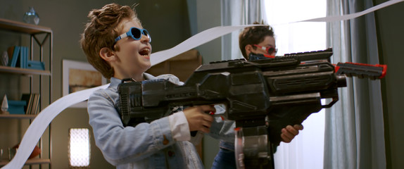 DOLLY OUT HERO SHOT Crazy Kids having a toy gunfight at home. Family having fun during quarantine,...