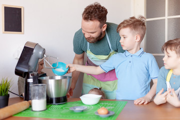 happy father with children cooks on paternity leave in the kitchen
