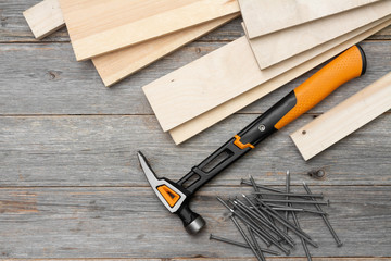 Carpentry tools hammer, nails, wooden bars, helmet and gloves on a gray wooden table