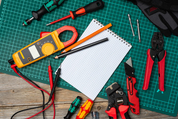 Electrician's or Builder's tools on the table. An electric tester, screwdrivers, tongs, construction tape measure, and a level are spread out on the table. The view from the top
