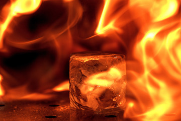 Close up big melting piece of ice on the bar counter in fireflames on it, preparation for a...
