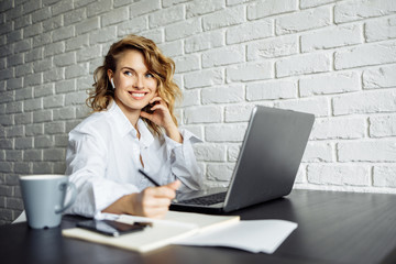 Freelancer woman sitting at table with laptop.