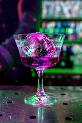 Close up of alcoholic cocktail, beverage, drink, prepared by professional barman in multicolored neon light. Entertainment, drinks, service concept. Modern bar, trendy neoned colors, copyspace.