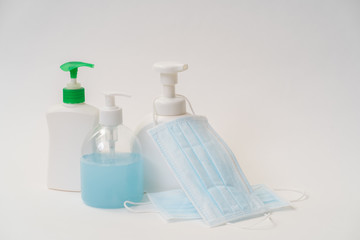 Surgical face mask and alcohol gel bottle on white background