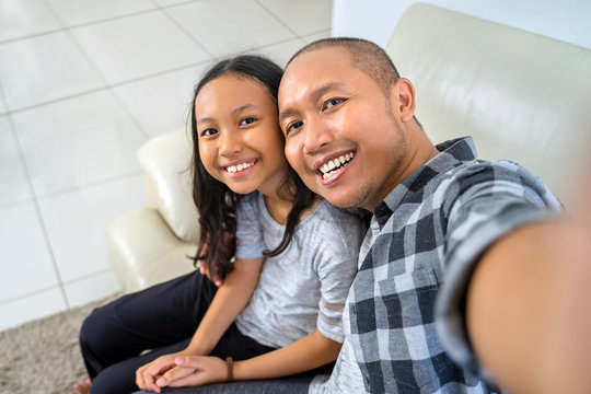 Happy child taking selfie with her father at home