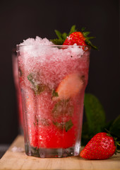 Glass of strawberry drink on a drak background. Fresh strawberry cocktail. Fresh summer cocktail with strawbery, ice and mint.