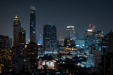 Panoramic view of Bangkok skyline at night time. Illuminated city center of capital of Thailand. Contemporary buildings exterior with glass.