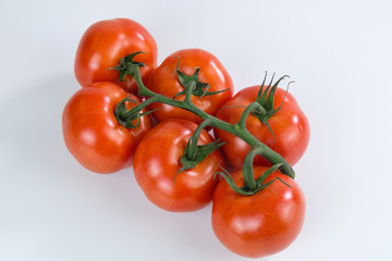 Rote Rispen-Tomaten mit Stengel auf weißem Untergrund