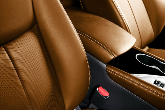 Luxury car brown leather interior. Part of leather car seat details with stitching. Comfortable perforated orange leather seats. Brown perforated leather. Car inside