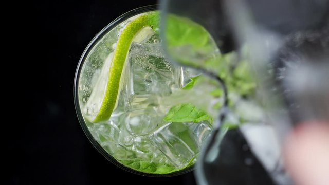 Close-up refreshing soda tonic. Pour carbonated water into a glass of lime and ice. Cold Mojito lemonade