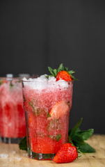 Glass of strawberry drink on a drak background. Fresh strawberry cocktail. Fresh summer cocktail with strawbery, ice and mint.