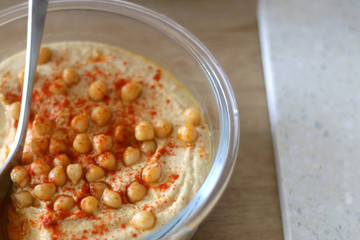 Bowl of homemade hummus served on a table. Selective focus.