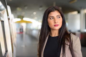 Profile view of young beautiful Indian businesswoman buying ticket at skytrain station