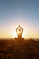 Silhouette meditation girl on the background of the stunning sea and sunset. Yoga, fitness and...