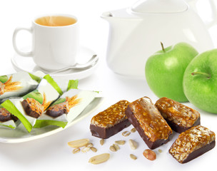 chocolate candies with cereals, nuts and apples on a white background composition