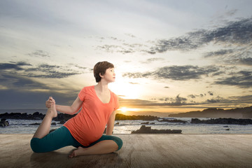Naklejka na ściany i meble Asian pregnant woman is practicing yoga