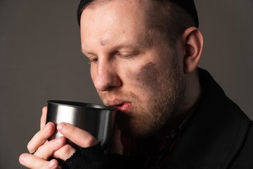 portrait of a unhappy unemployed man who drinks from a tin mug. The concept of survival of the poor on the street