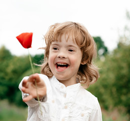 A boy of 5 years gives a flower, red poppy, a happy child. Down Syndrome. Childhood. Toning.