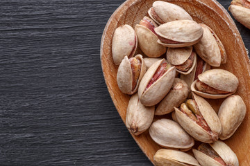 Pistachios nuts on dark background, top view, healthy snack. Space for text
