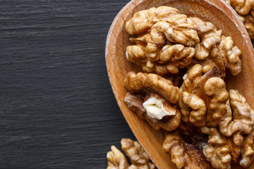 Walnut in wooden bowl on black background with copy space.Top view. Wooden plate with walnut on black background. Space for text