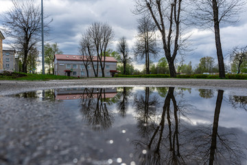 Obraz premium Street view with water reflection after rain in Estonia. Summer Rain Showers, urban view. Old soviet town.