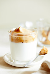 Trendy whipped Korean Dalgona drink with foam of instant coffee on beige background close-up selective focus