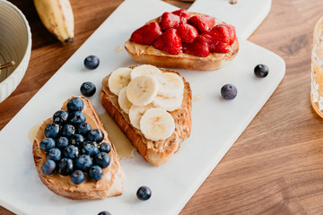 Toasts with peanut butter, blueberry, strawberry and banana. Healthy breakfast concept.