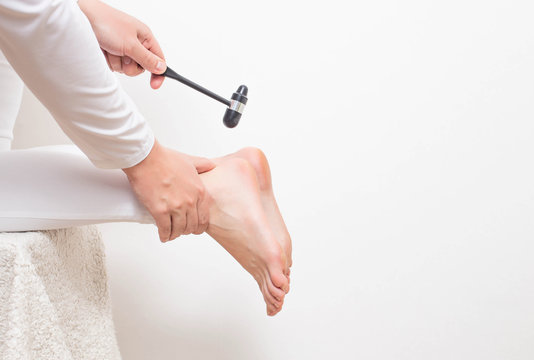 A neurologist doctor checks the Achilles reflex with a neurological hammer. Checking the tibial nerve and the presence of an intervertebral hernia of the spine, copy space