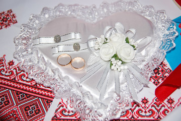 Wedding rings lie on a pillow in the form of a heart. Ukrainian wedding embroidery close up.